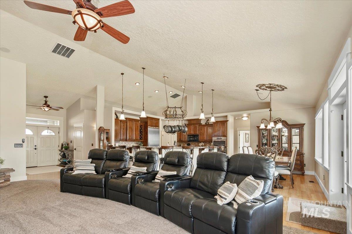 Living area with a chandelier, ceiling fan, a textured ceiling, high vaulted ceiling, and plenty of natural light