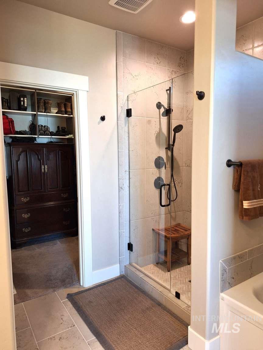 Full bathroom featuring a shower stall and light tile patterned floors