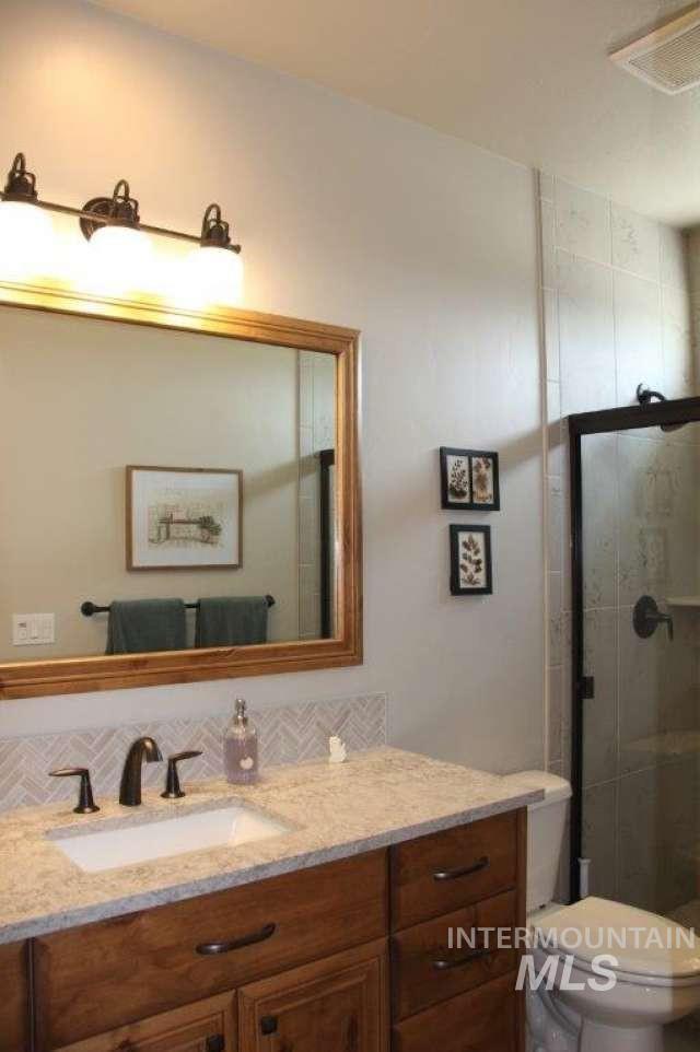 Full bath with vanity, a shower stall, and backsplash