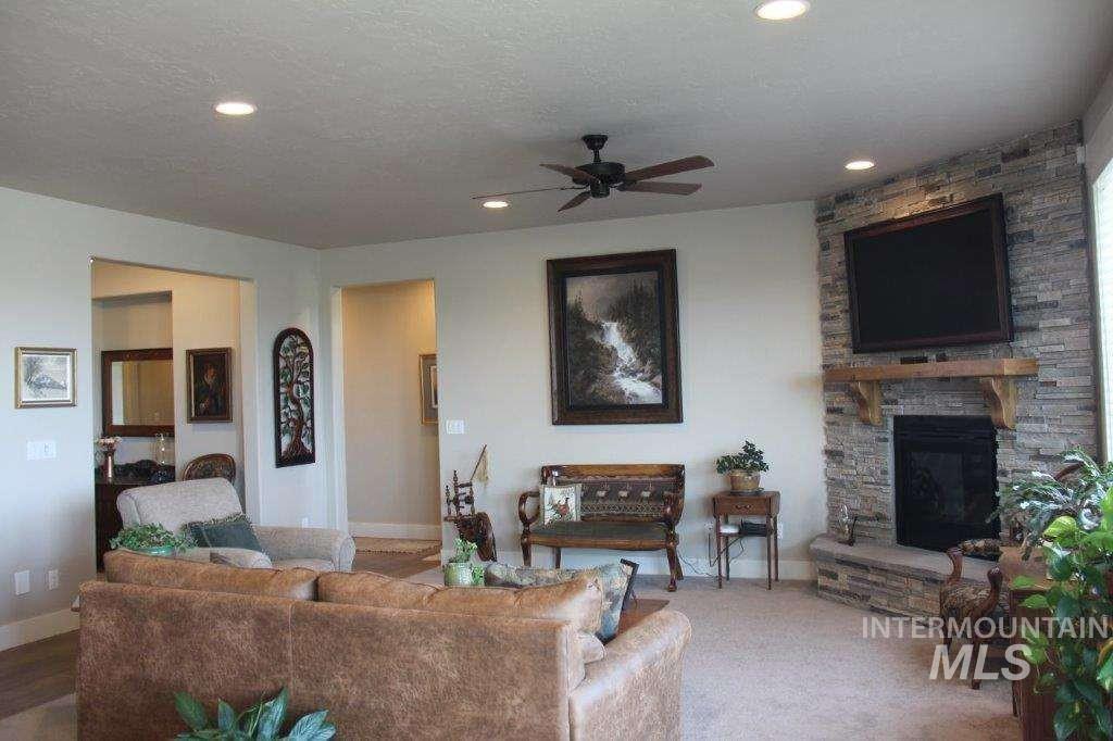 Living area with a ceiling fan, a fireplace, a textured ceiling, and recessed lighting