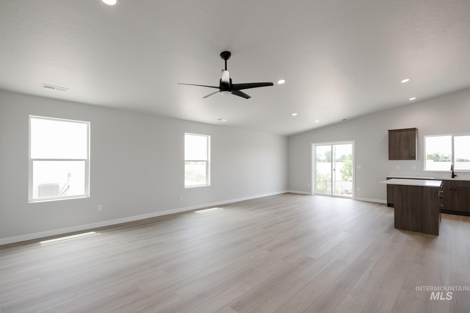 Unfurnished living room featuring ceiling fan, light wood-style floors, recessed lighting, and lofted ceiling