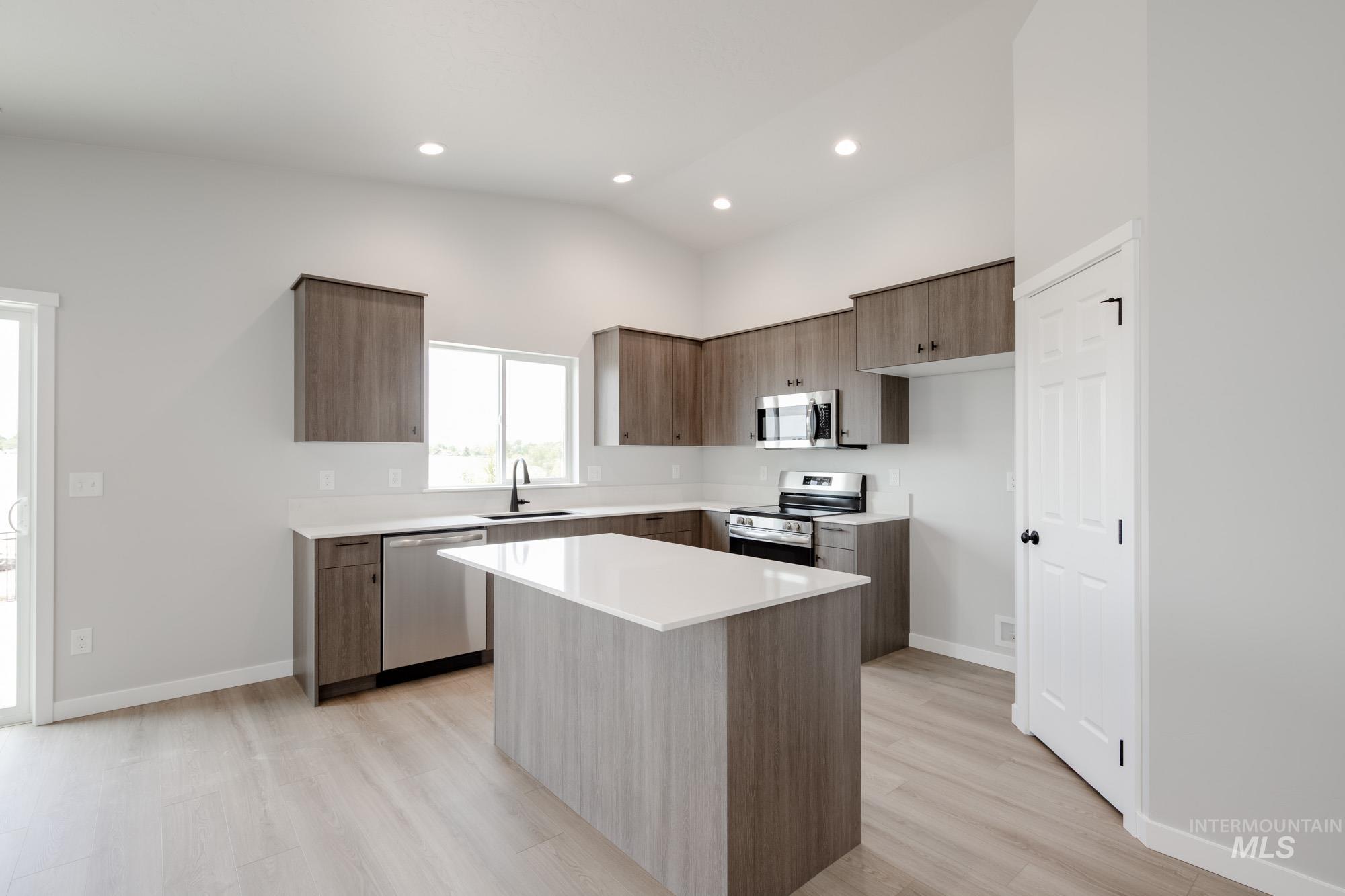 Kitchen featuring appliances with stainless steel finishes, light wood-type flooring, modern cabinets, light countertops, and recessed lighting