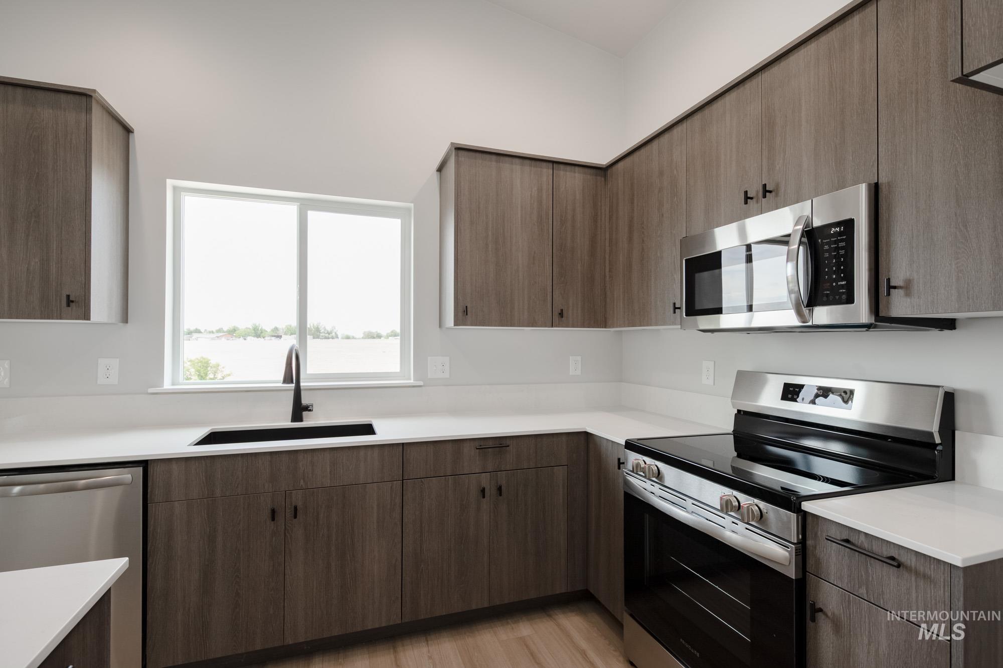 Kitchen with appliances with stainless steel finishes, light countertops, and light wood-style floors