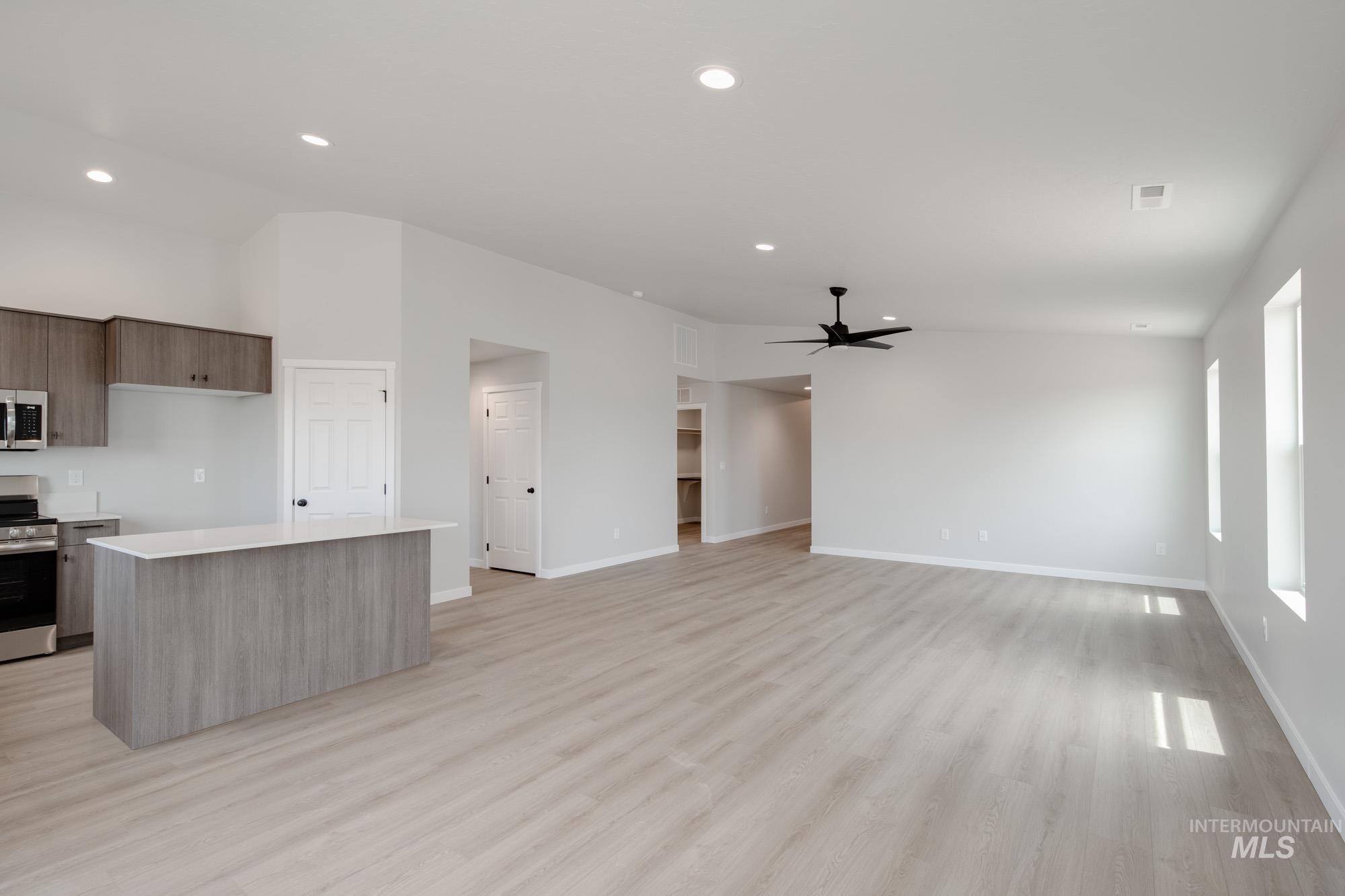 Kitchen with stainless steel appliances, modern cabinets, light countertops, ceiling fan, and recessed lighting