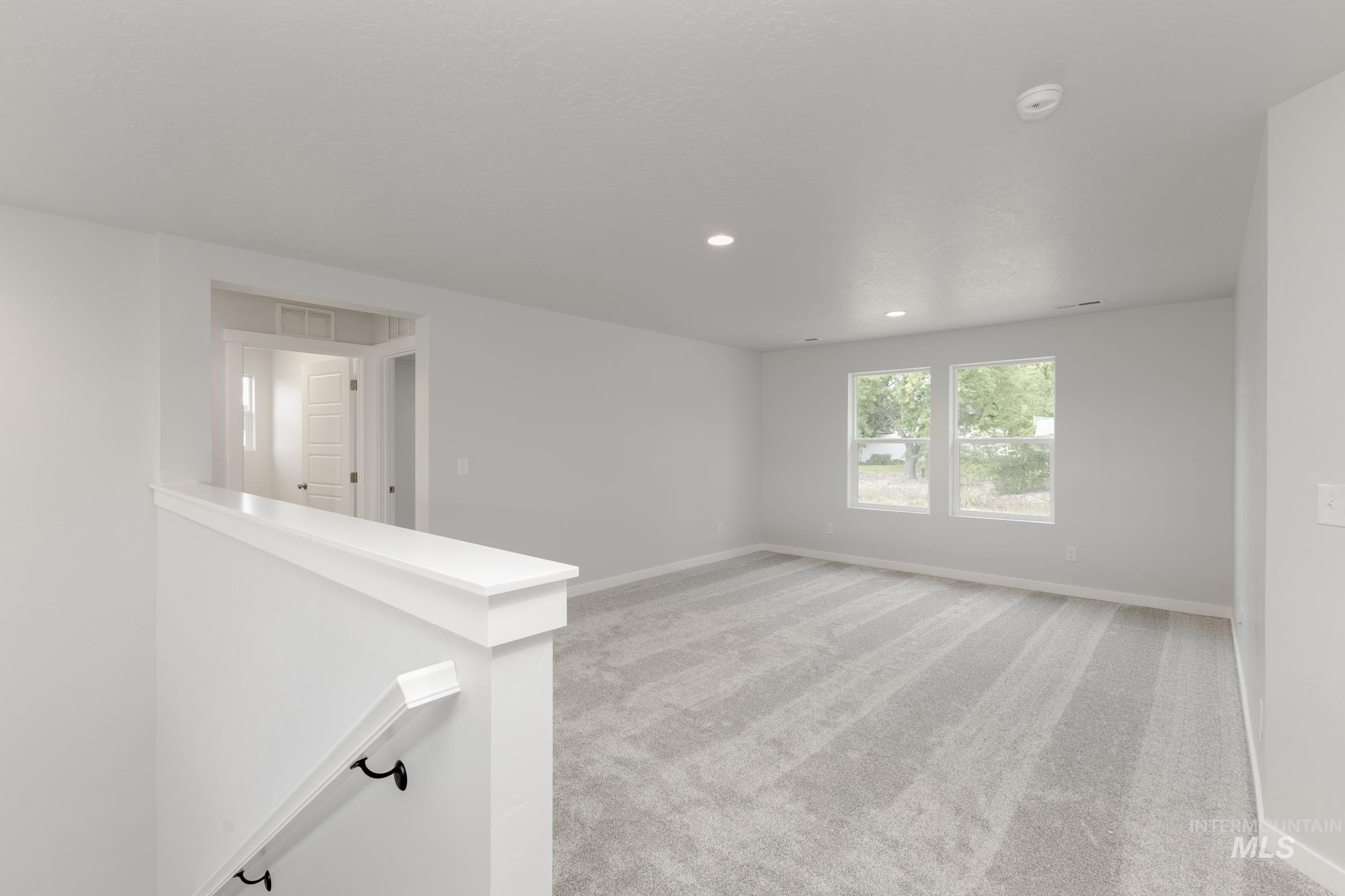 Empty room with a smoke detector, light colored carpet, and recessed lighting