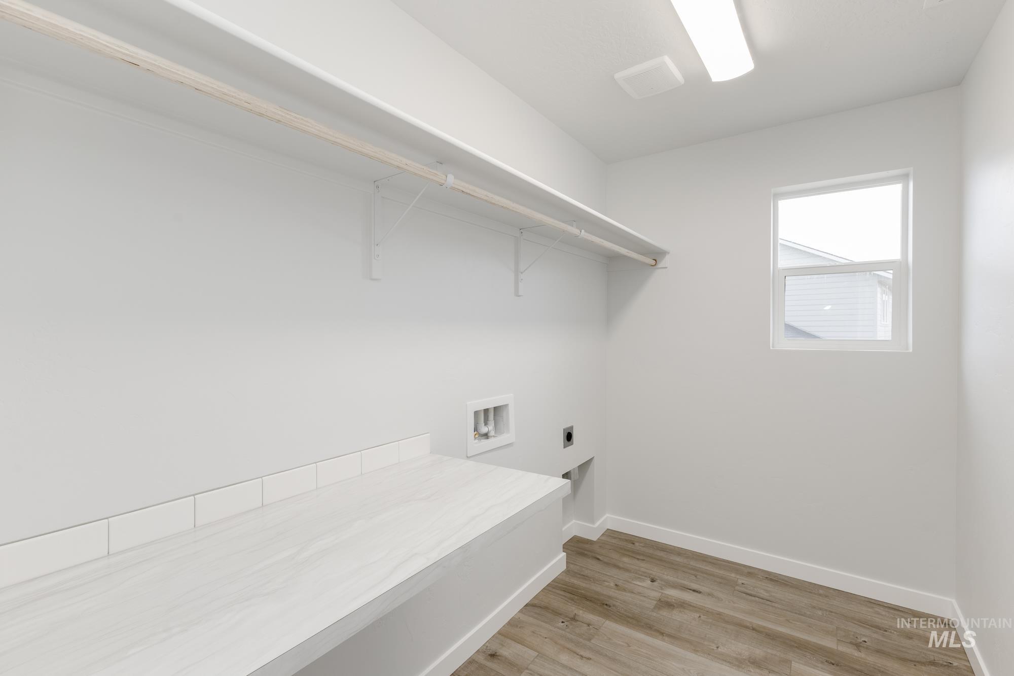 Laundry room featuring electric dryer hookup, washer hookup, and light wood-type flooring