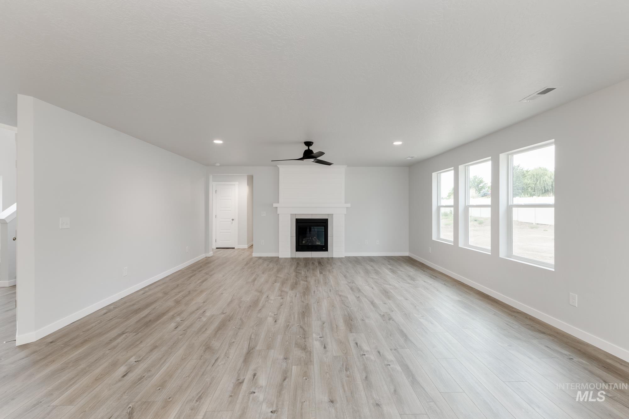 Unfurnished living room featuring light wood finished floors, ceiling fan, recessed lighting, and a large fireplace