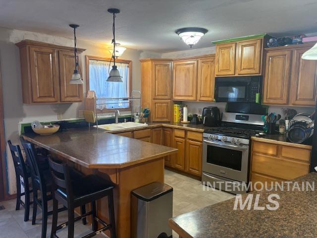 Kitchen with hanging light fixtures, brown cabinetry, stainless steel gas range oven, and a peninsula