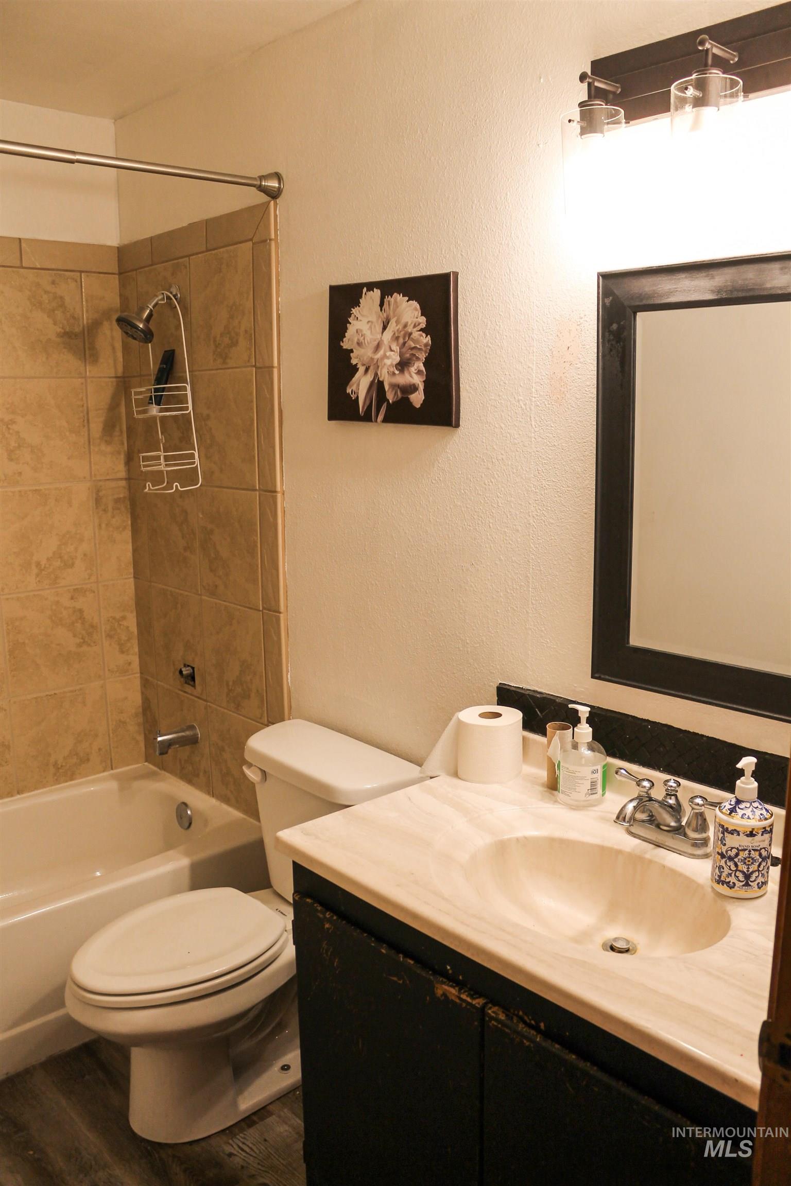 Bathroom with vanity, shower / bath combination, and wood finished floors