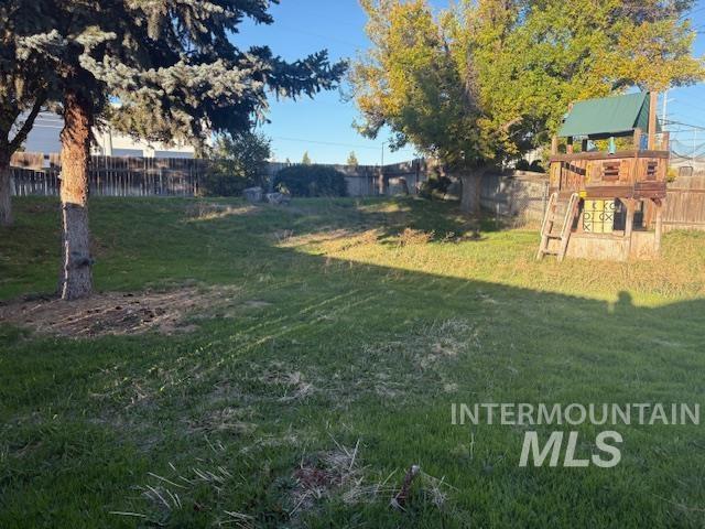 Fenced backyard featuring a playground