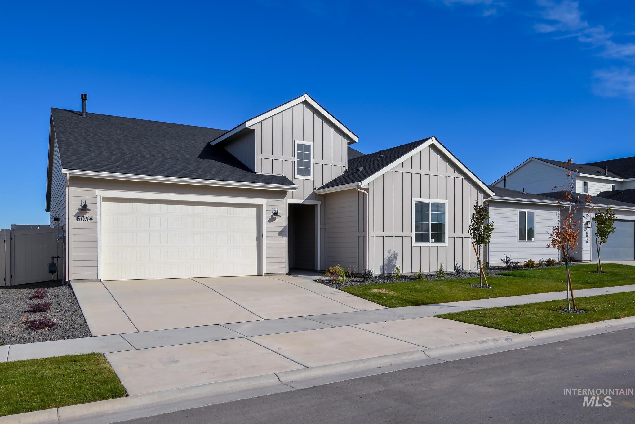 Modern inspired farmhouse featuring board and batten siding, concrete driveway, a garage, a front yard, and roof with shingles