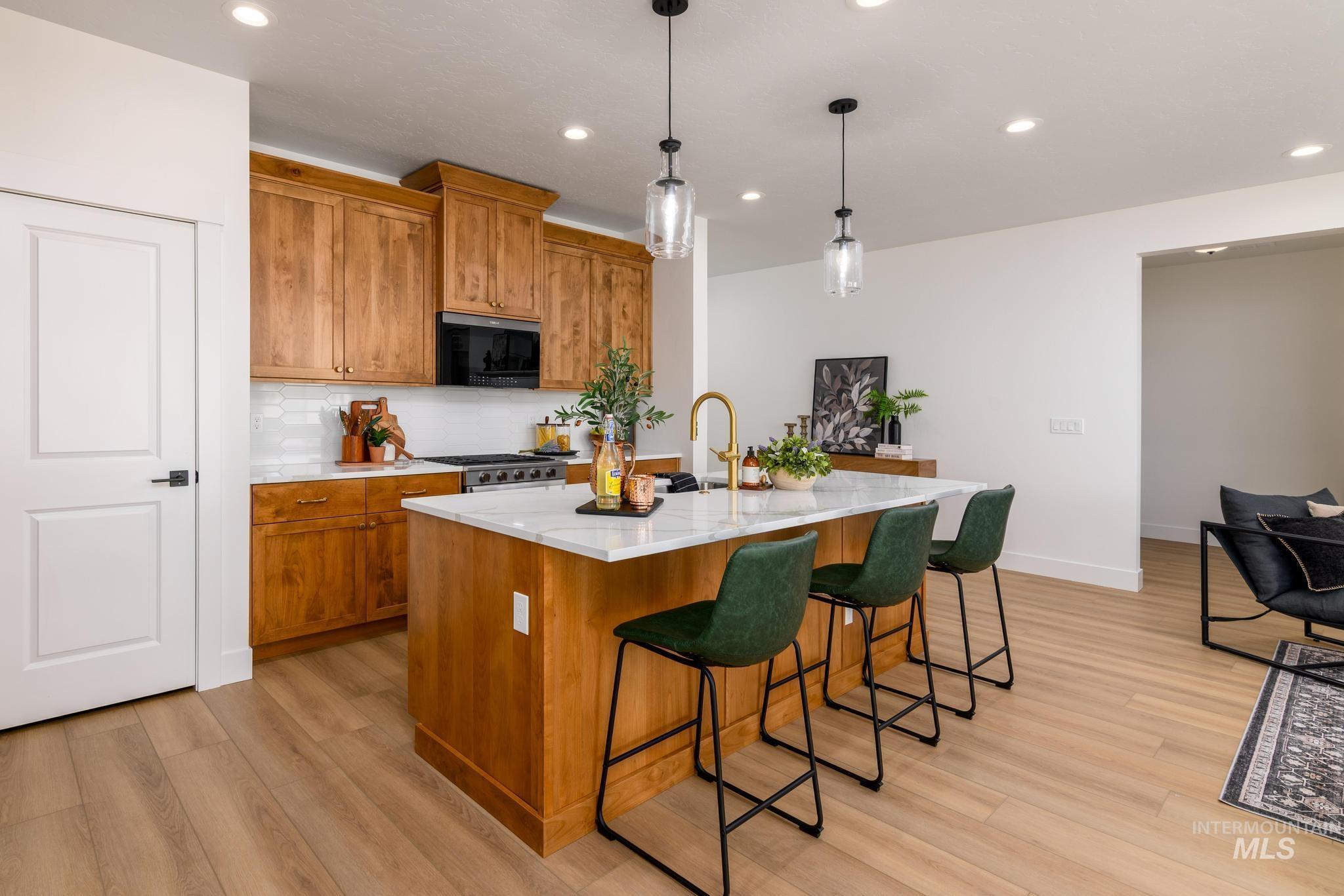 Kitchen with brown cabinetry, recessed lighting, tasteful backsplash, decorative light fixtures, and light wood-type flooring