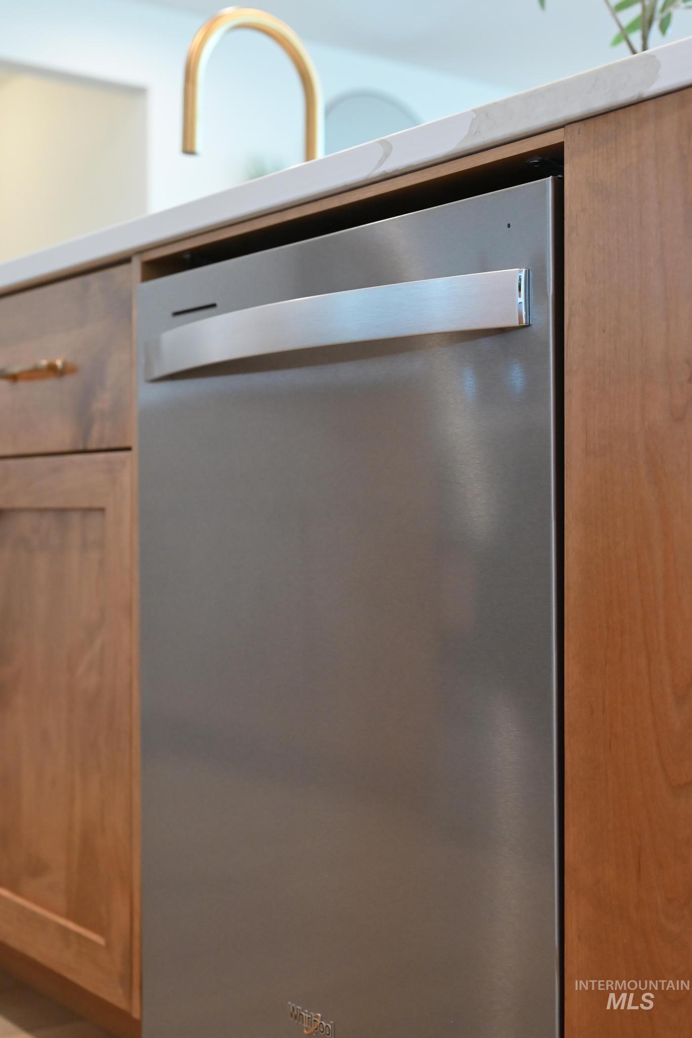 Kitchen view of dishwasher, brown cabinets, and light countertops