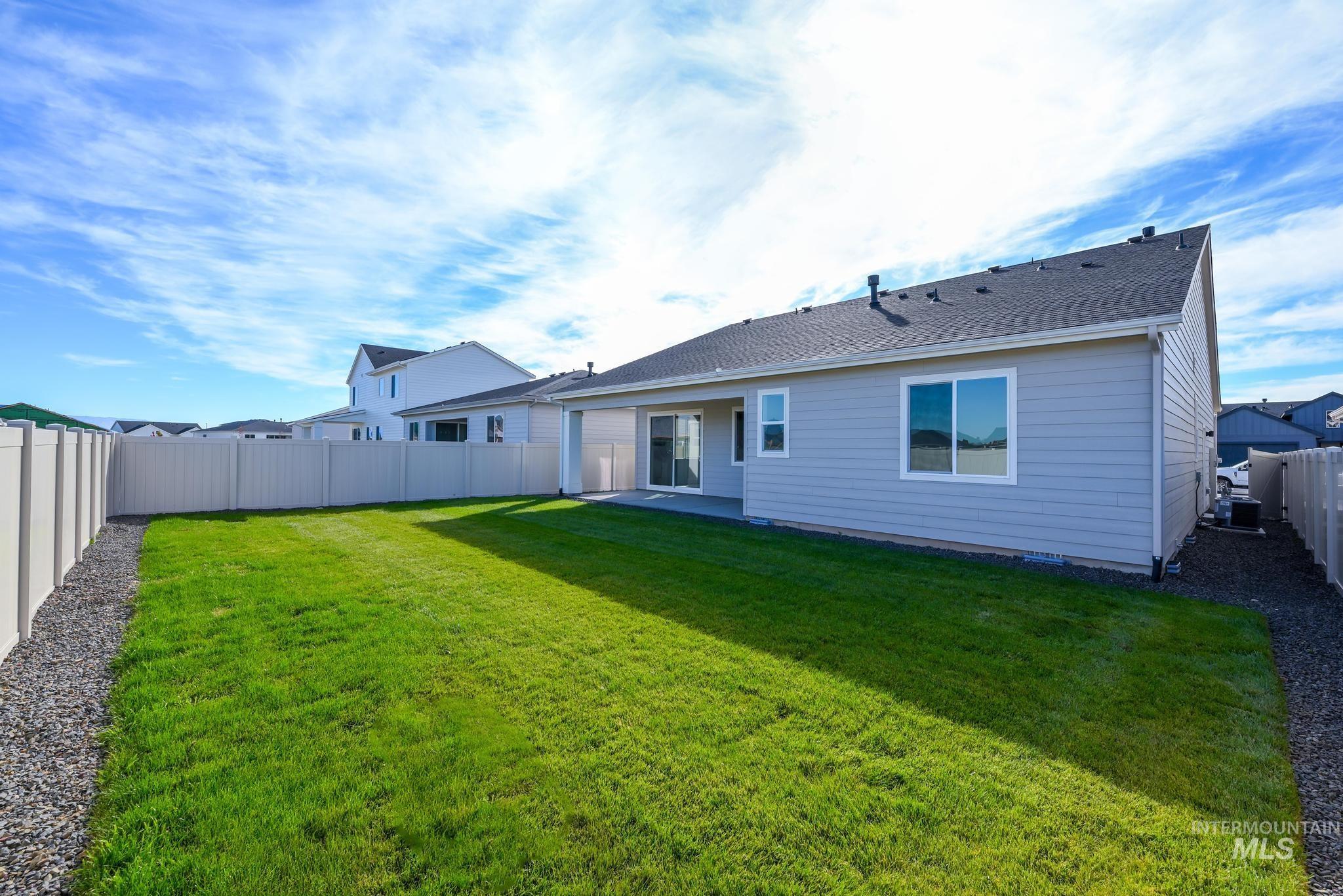 Rear view of house with a patio, a fenced backyard, and a shingled roof