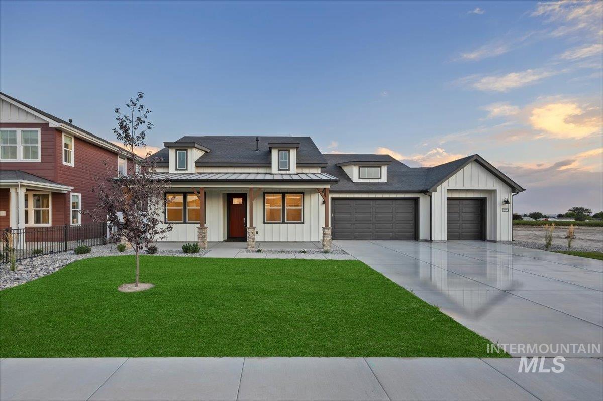 Modern farmhouse style home featuring board and batten siding, a garage, covered porch, and driveway