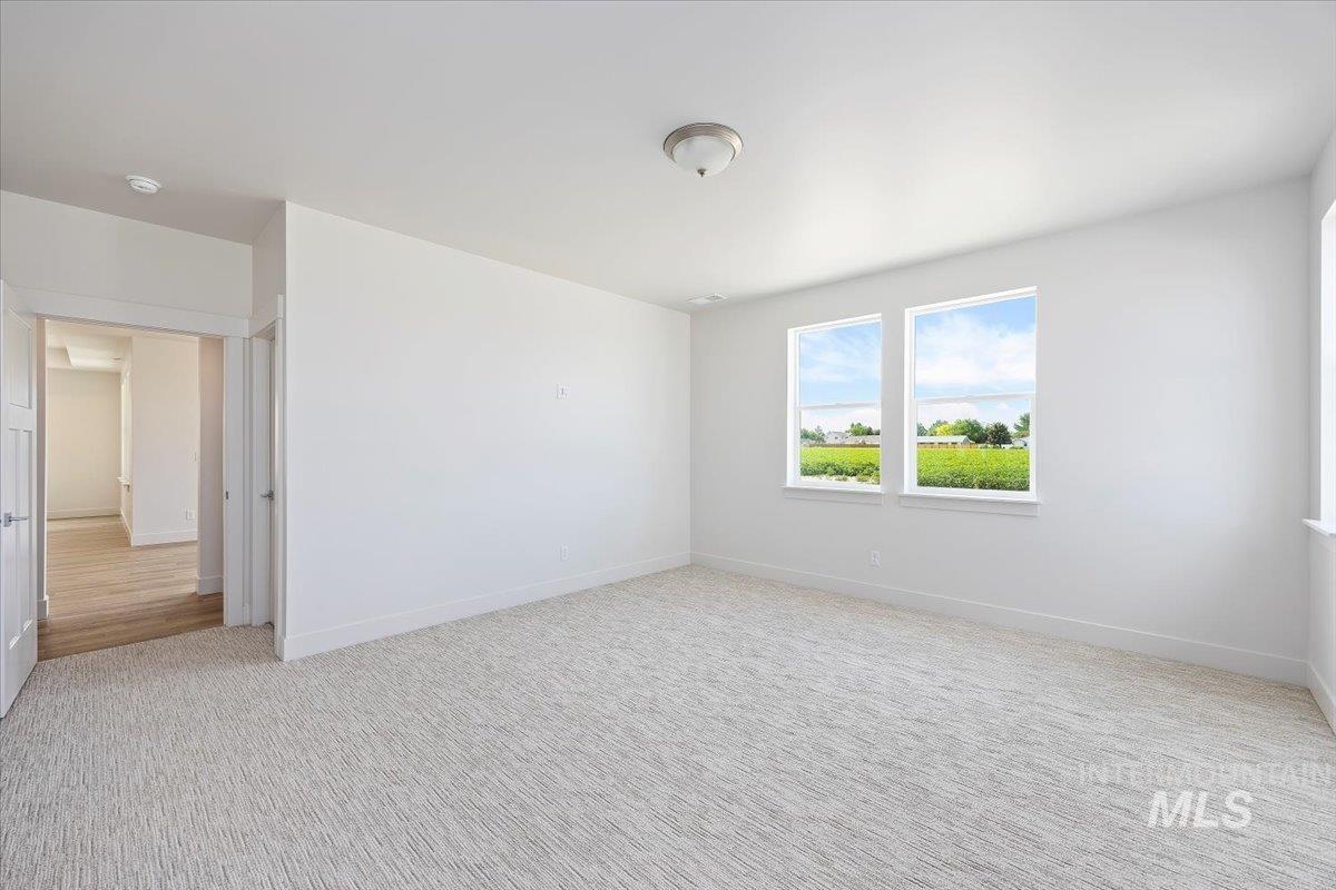 Empty room featuring light colored carpet and baseboards