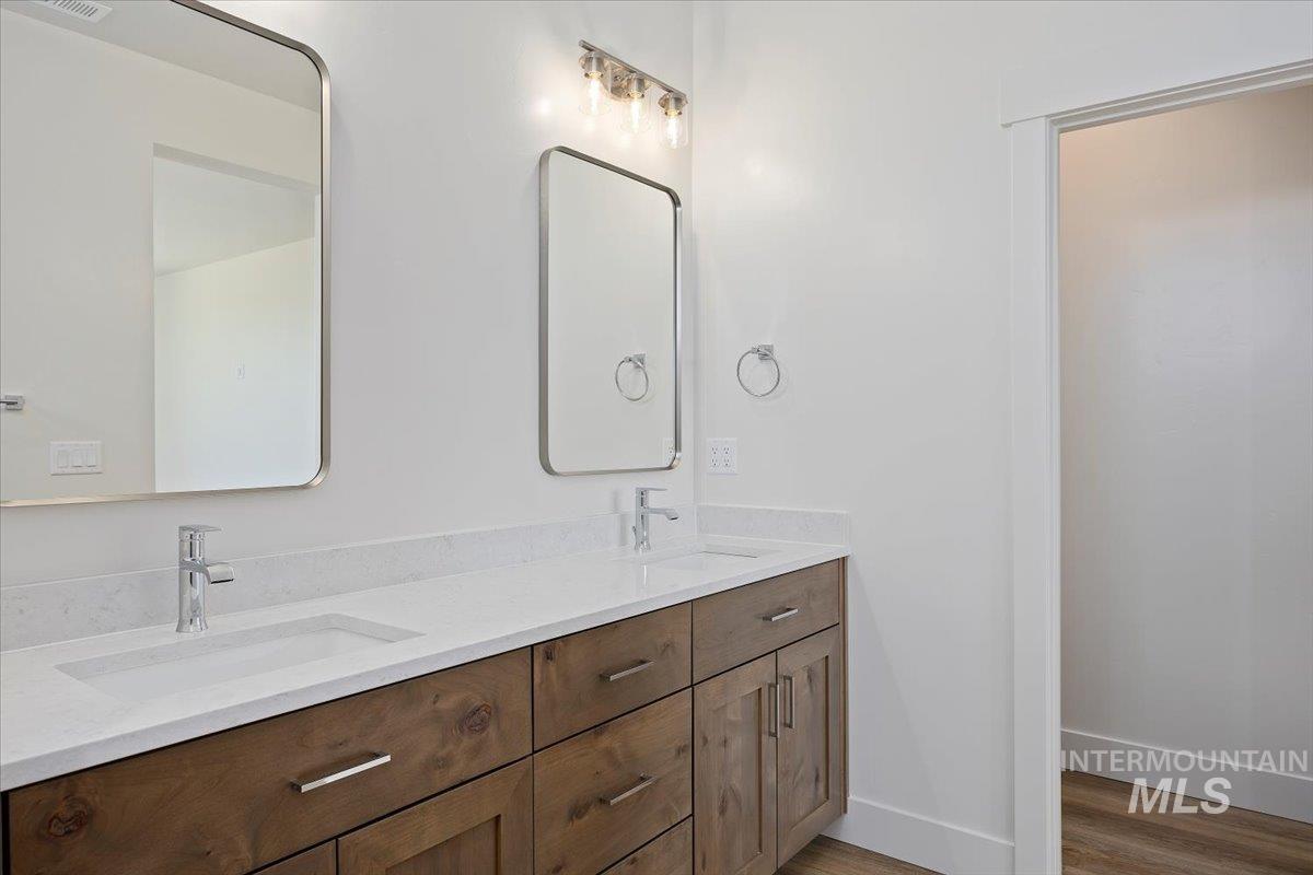 Full bathroom with double vanity and wood finished floors