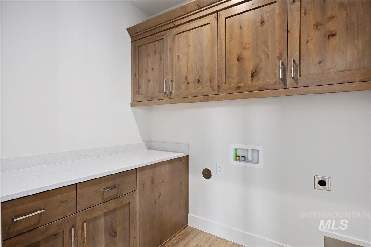 Laundry area with cabinet space, electric dryer hookup, hookup for a washing machine, and light wood finished floors