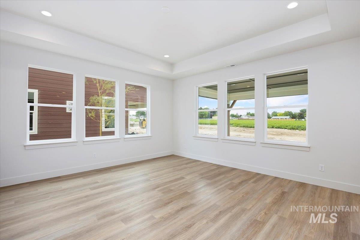 Unfurnished room featuring light wood finished floors, a raised ceiling, and recessed lighting