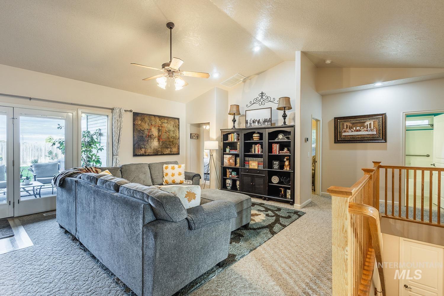 Carpeted living area featuring a ceiling fan and high vaulted ceiling