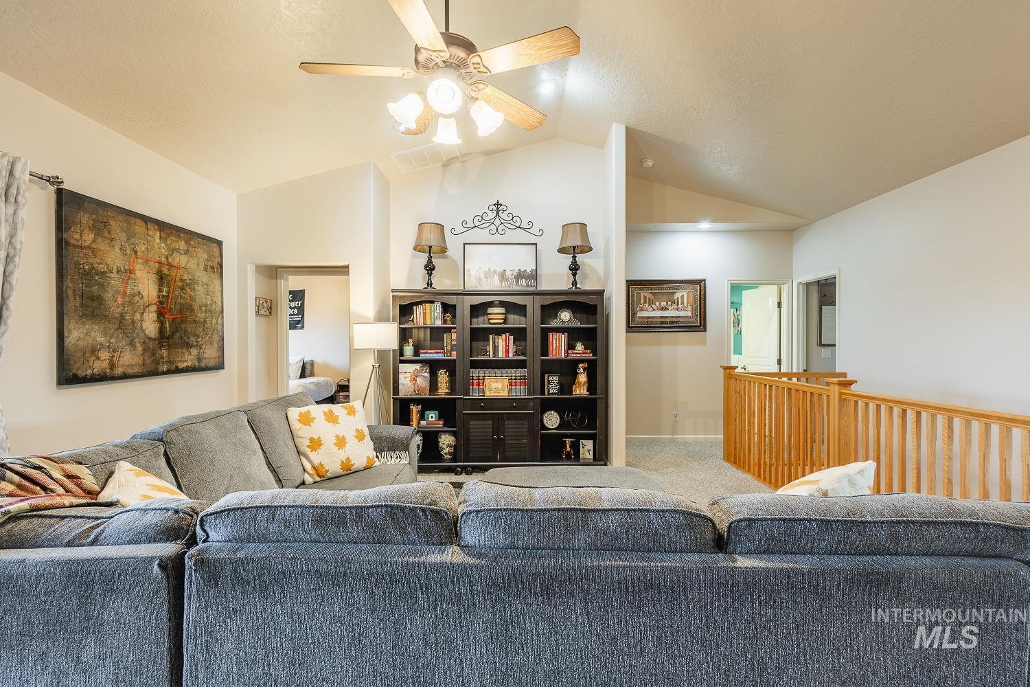 Carpeted living area with a ceiling fan and lofted ceiling
