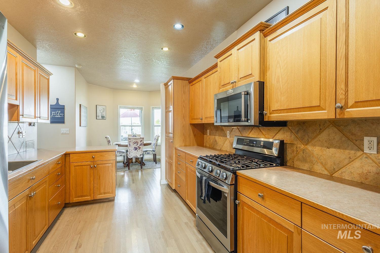 Kitchen with appliances with stainless steel finishes, light countertops, backsplash, recessed lighting, and a peninsula
