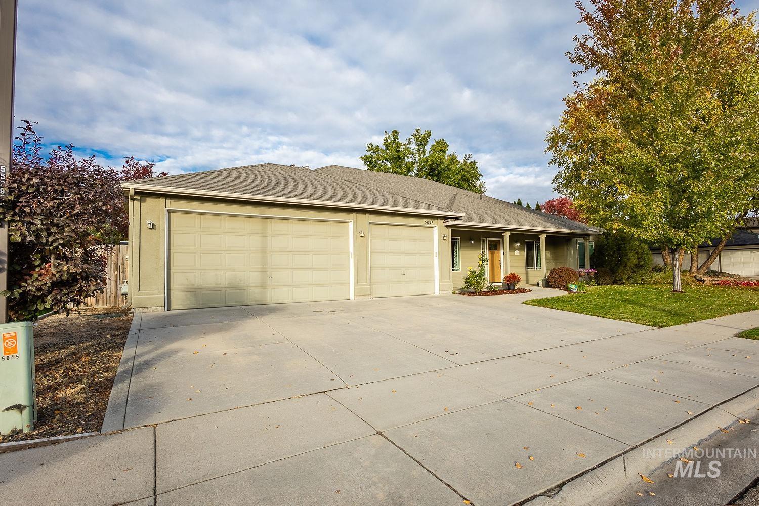 Ranch-style house featuring concrete driveway, a shingled roof, a porch, an attached garage, and a front yard