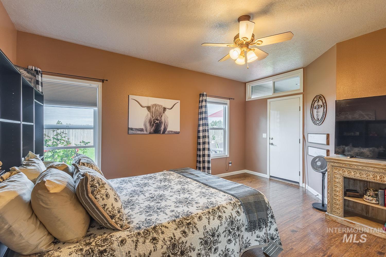 Bedroom featuring wood finished floors, a textured ceiling, and a ceiling fan