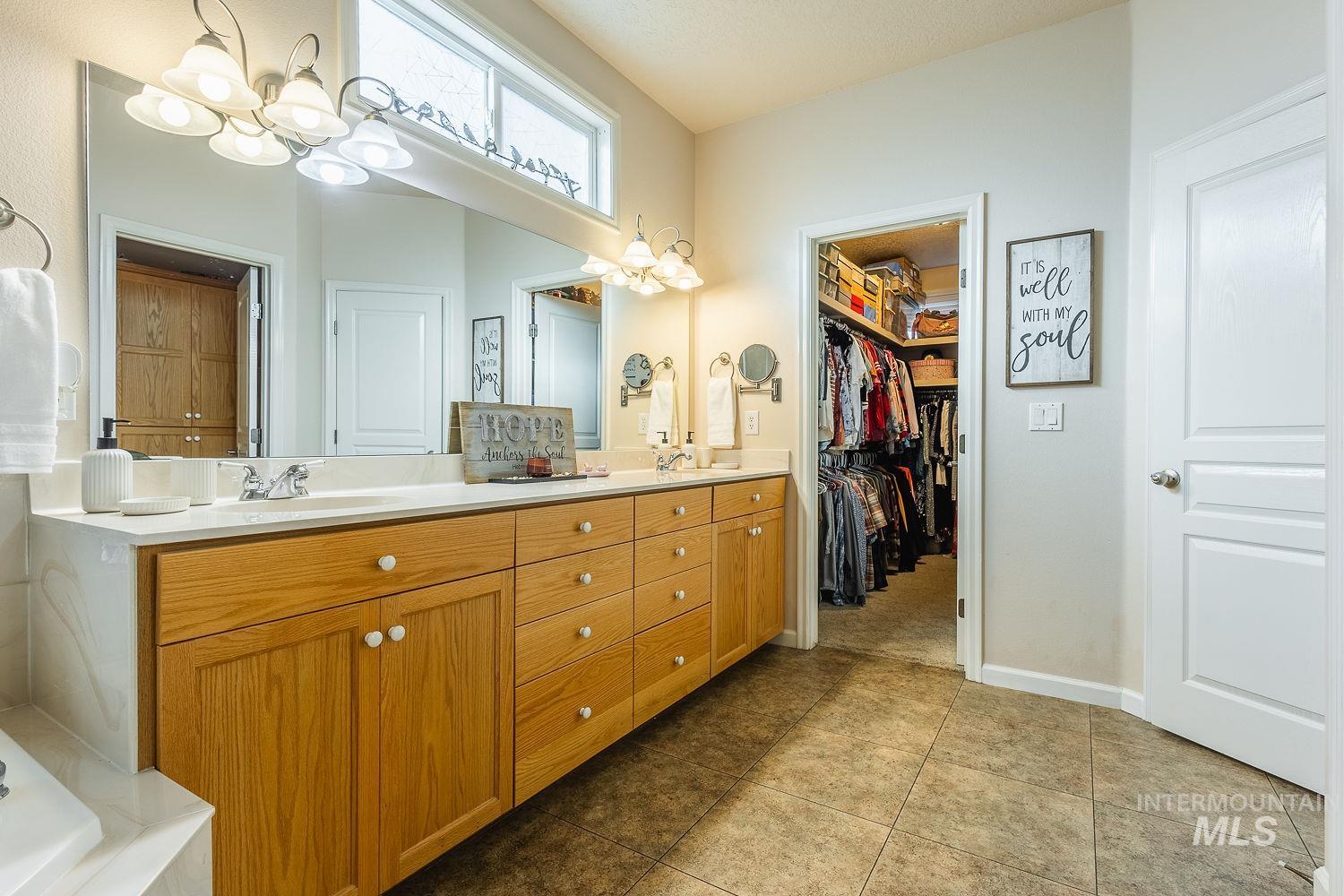 Full bathroom featuring a chandelier, double vanity, a walk in closet, and light tile patterned floors