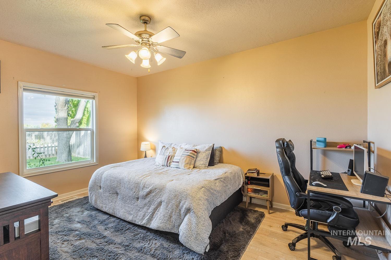 Bedroom with light wood-style flooring, a desk, a textured ceiling, and ceiling fan