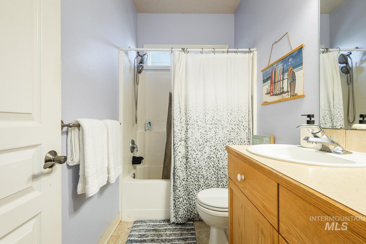 Full bathroom with vanity, shower / bath combination with curtain, and light tile patterned flooring