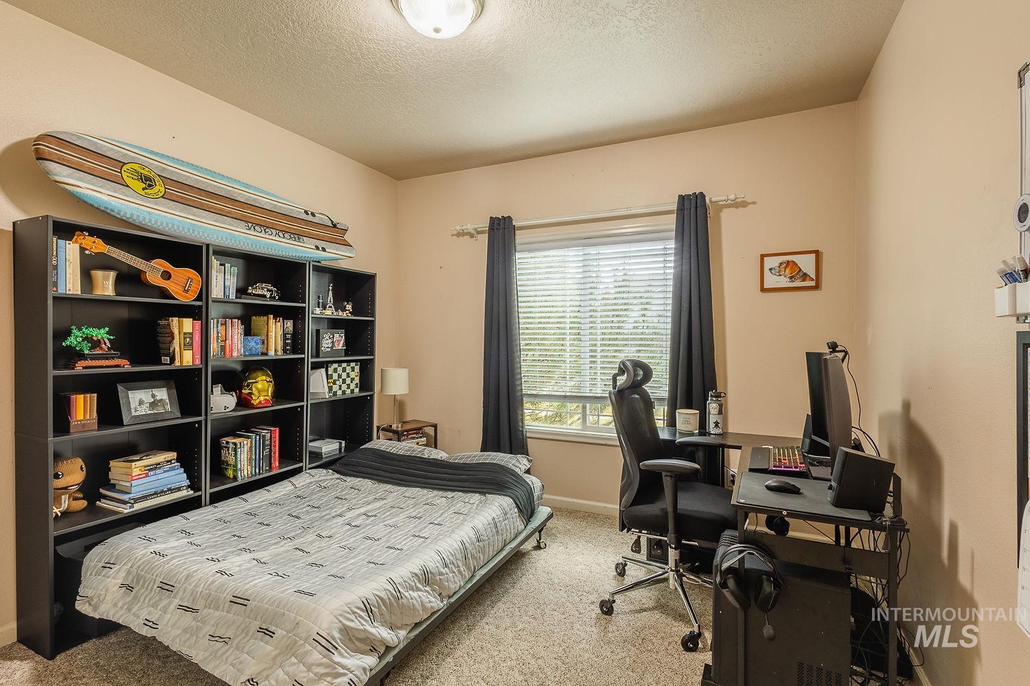 Bedroom featuring light carpet, a textured ceiling, and an office area