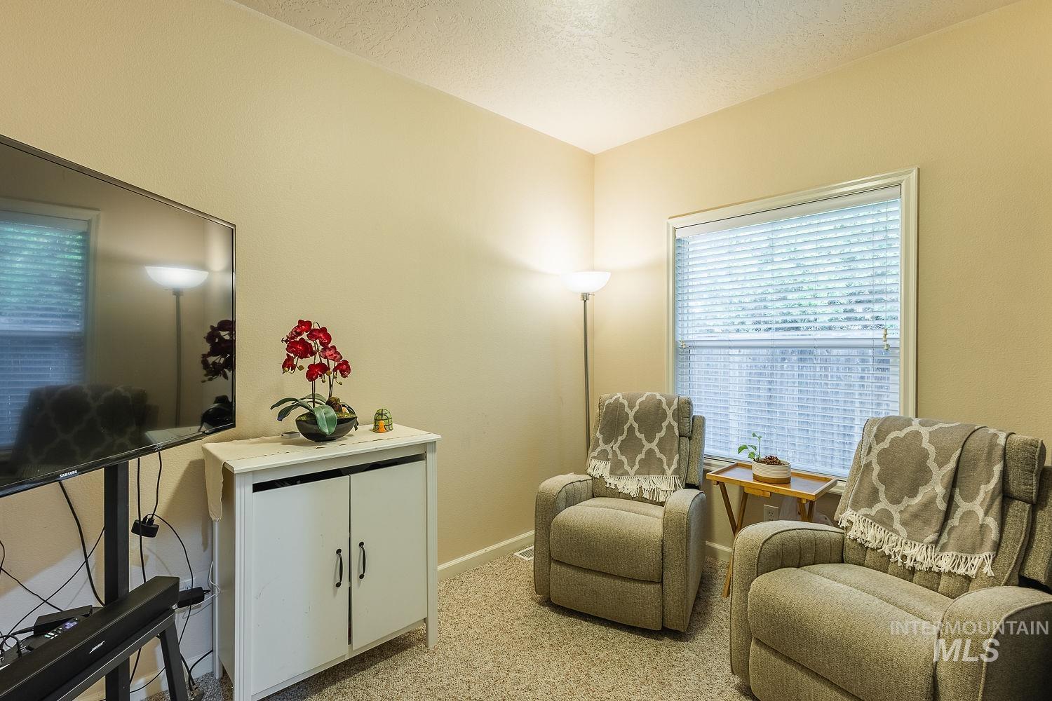 Sitting room featuring light carpet and a textured ceiling