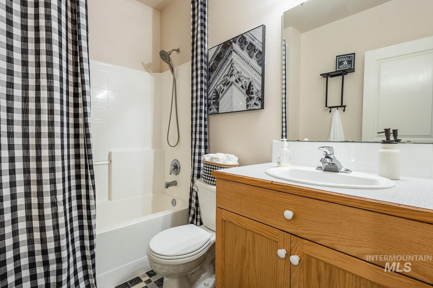 Full bath featuring shower / bathtub combination with curtain, vanity, and tile patterned floors