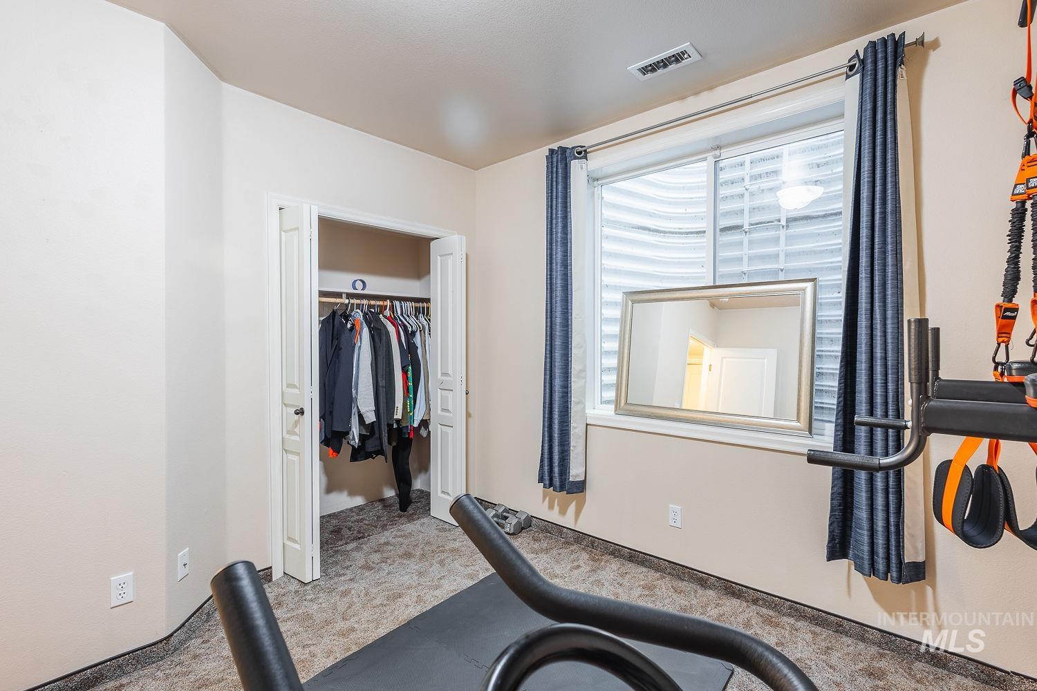 Exercise room featuring light carpet and baseboards