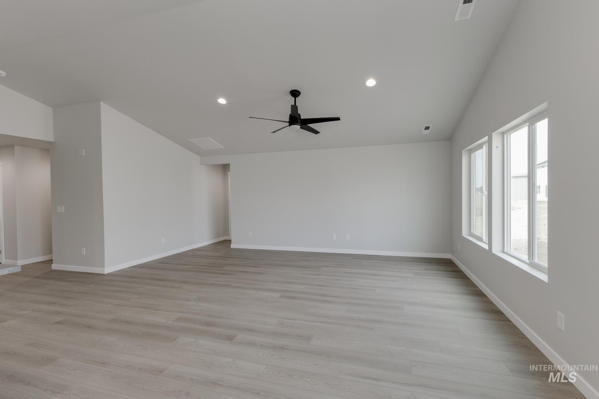 Empty room with a ceiling fan, recessed lighting, vaulted ceiling, and light wood-type flooring