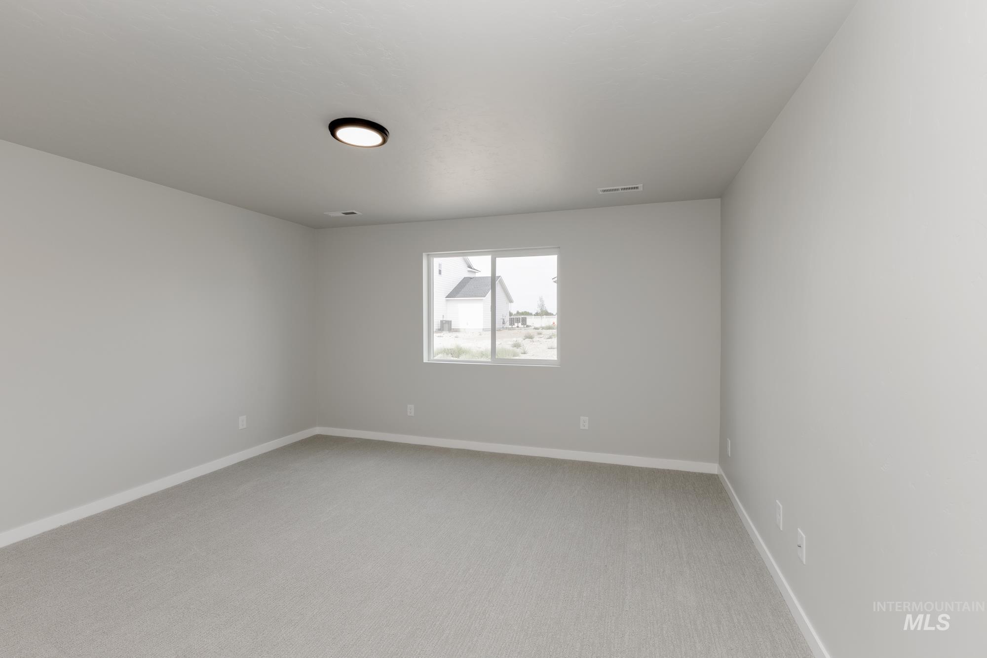 Spare room featuring light colored carpet and baseboards