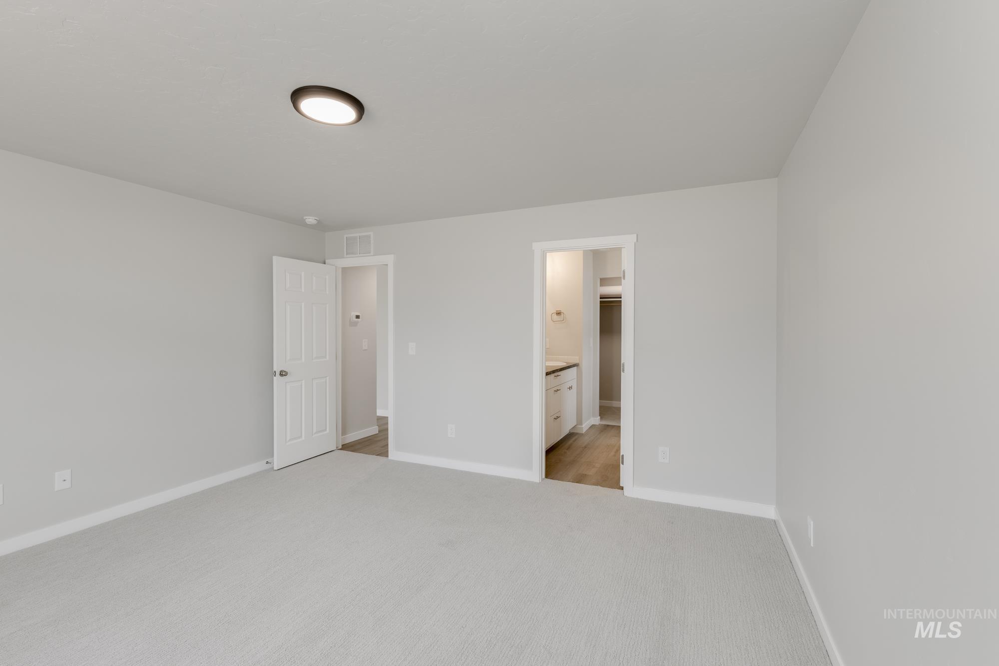 Unfurnished bedroom featuring light carpet and ensuite bath