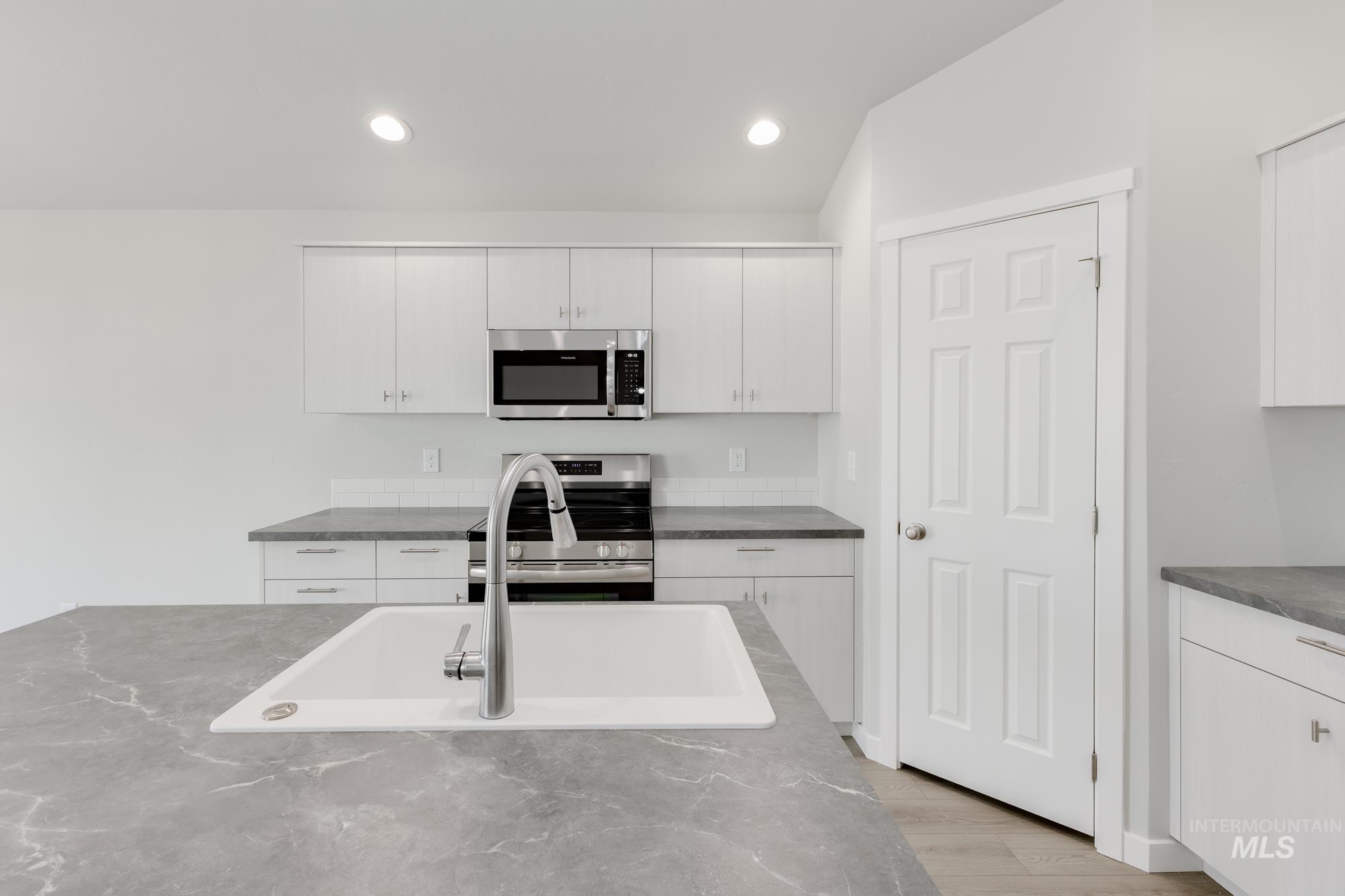 Kitchen featuring appliances with stainless steel finishes, white cabinetry, wood finished floors, and recessed lighting