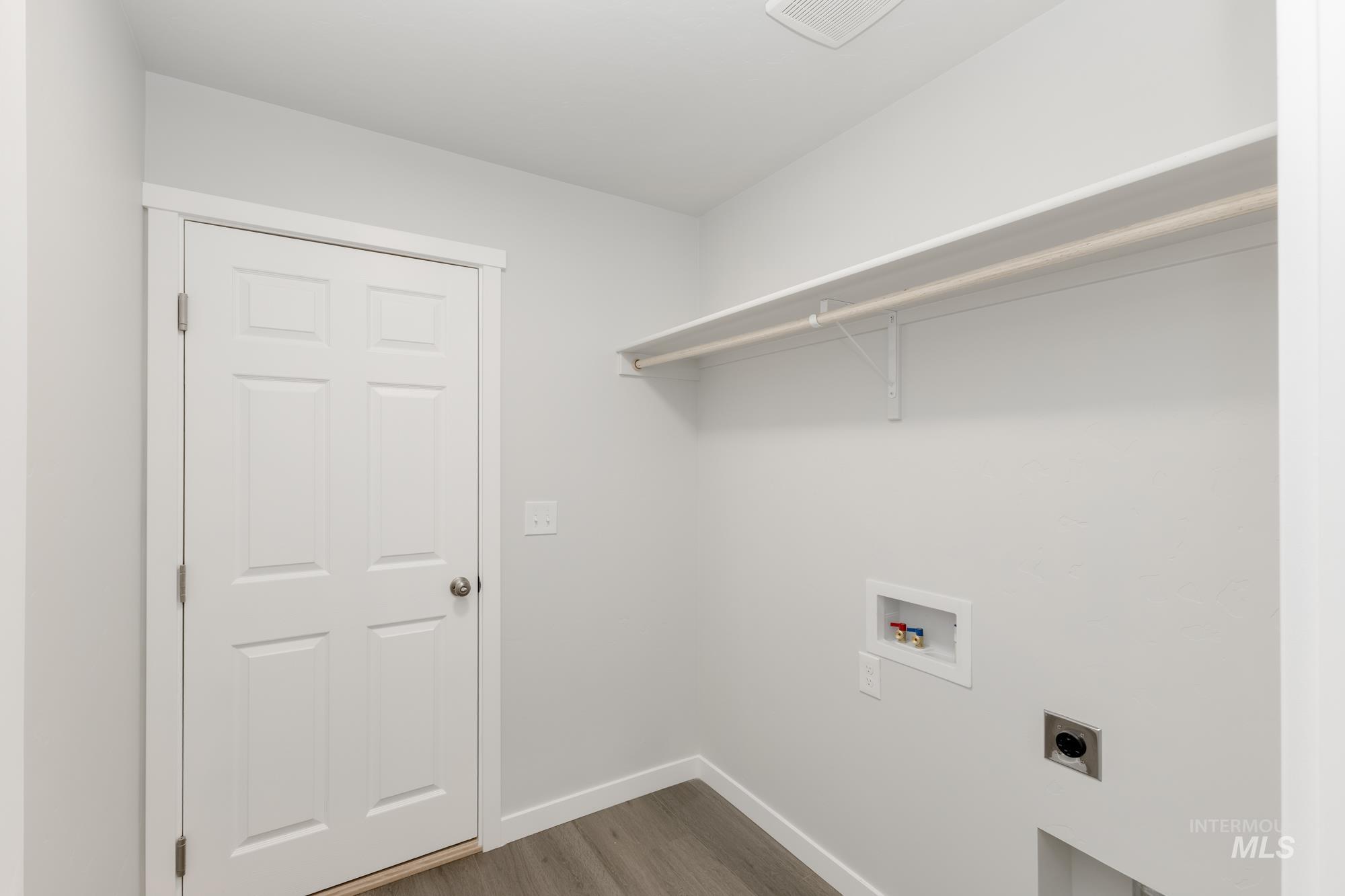 Laundry area with hookup for an electric dryer, hookup for a washing machine, and dark wood finished floors