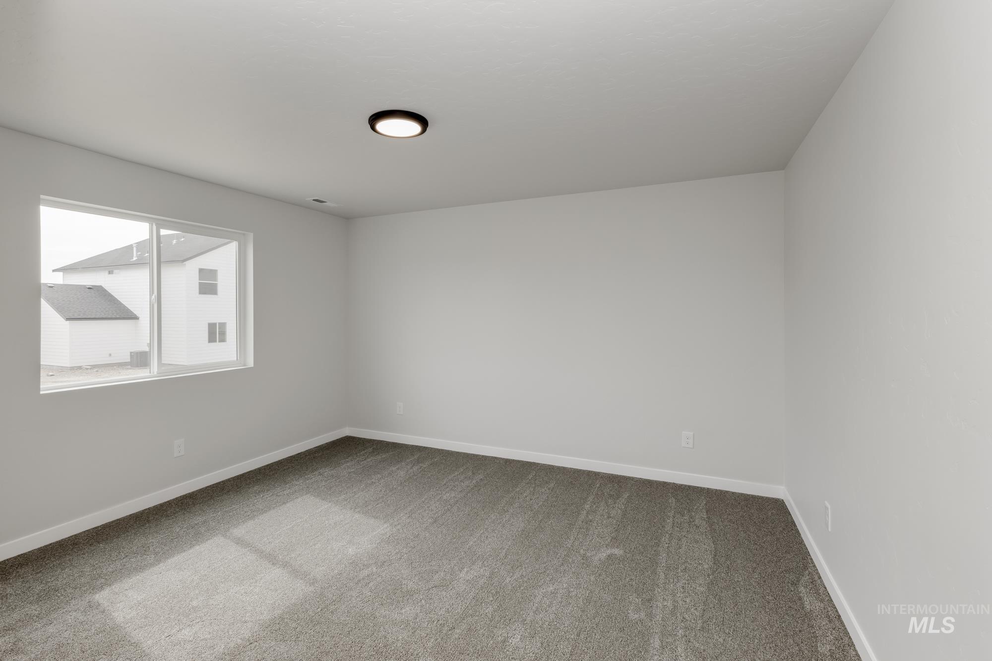 Empty room featuring dark carpet and baseboards