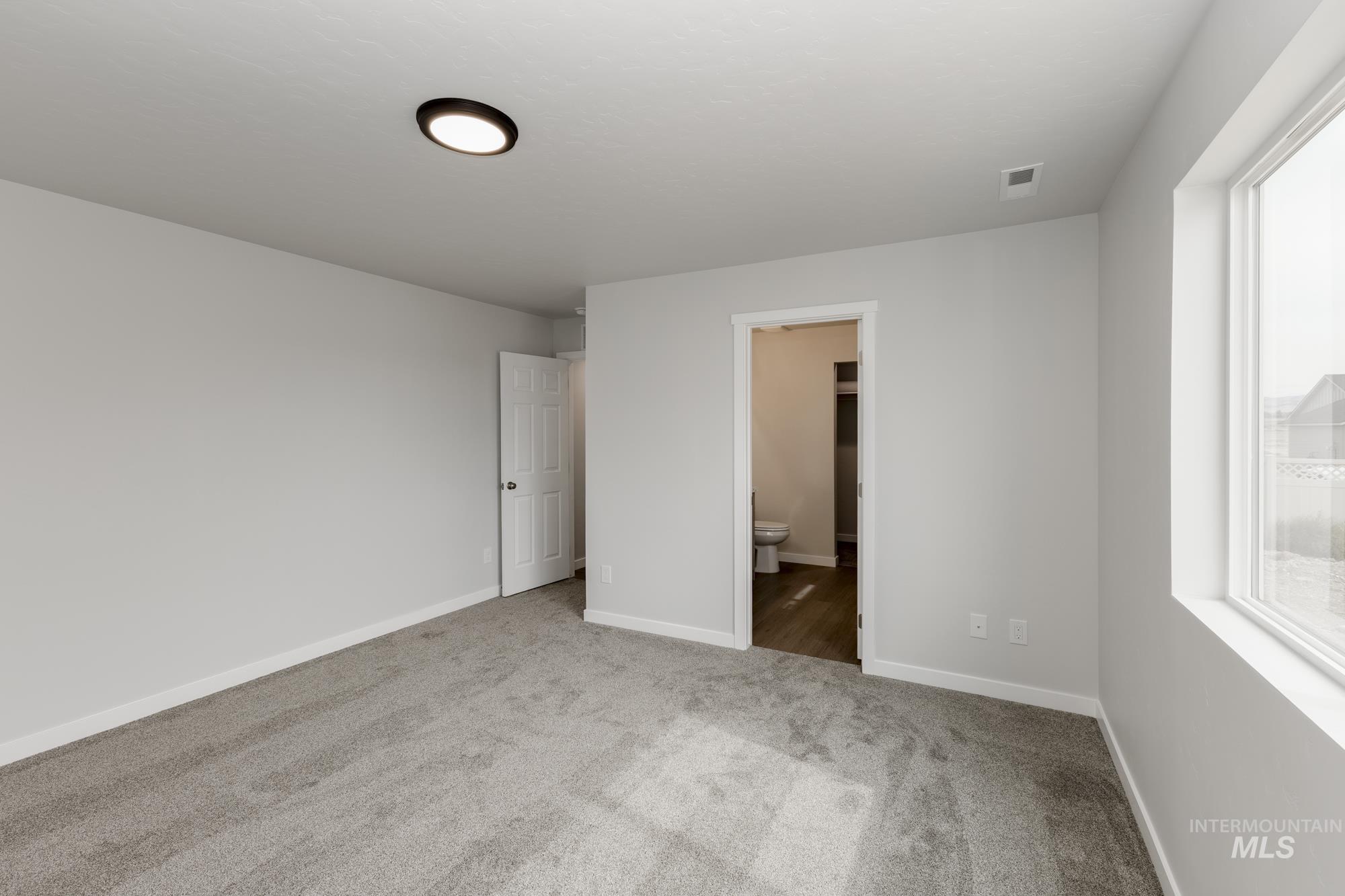Unfurnished bedroom with carpet and connected bathroom