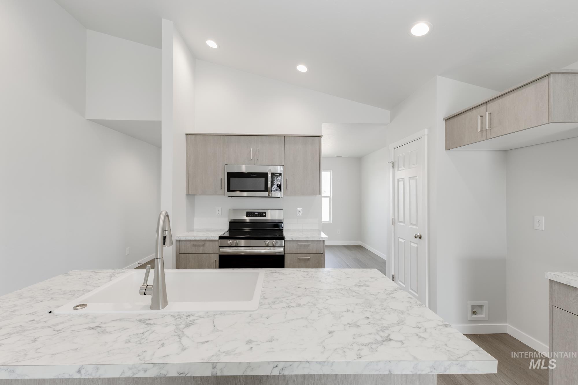 Kitchen with appliances with stainless steel finishes, wood finished floors, light countertops, modern cabinets, and recessed lighting