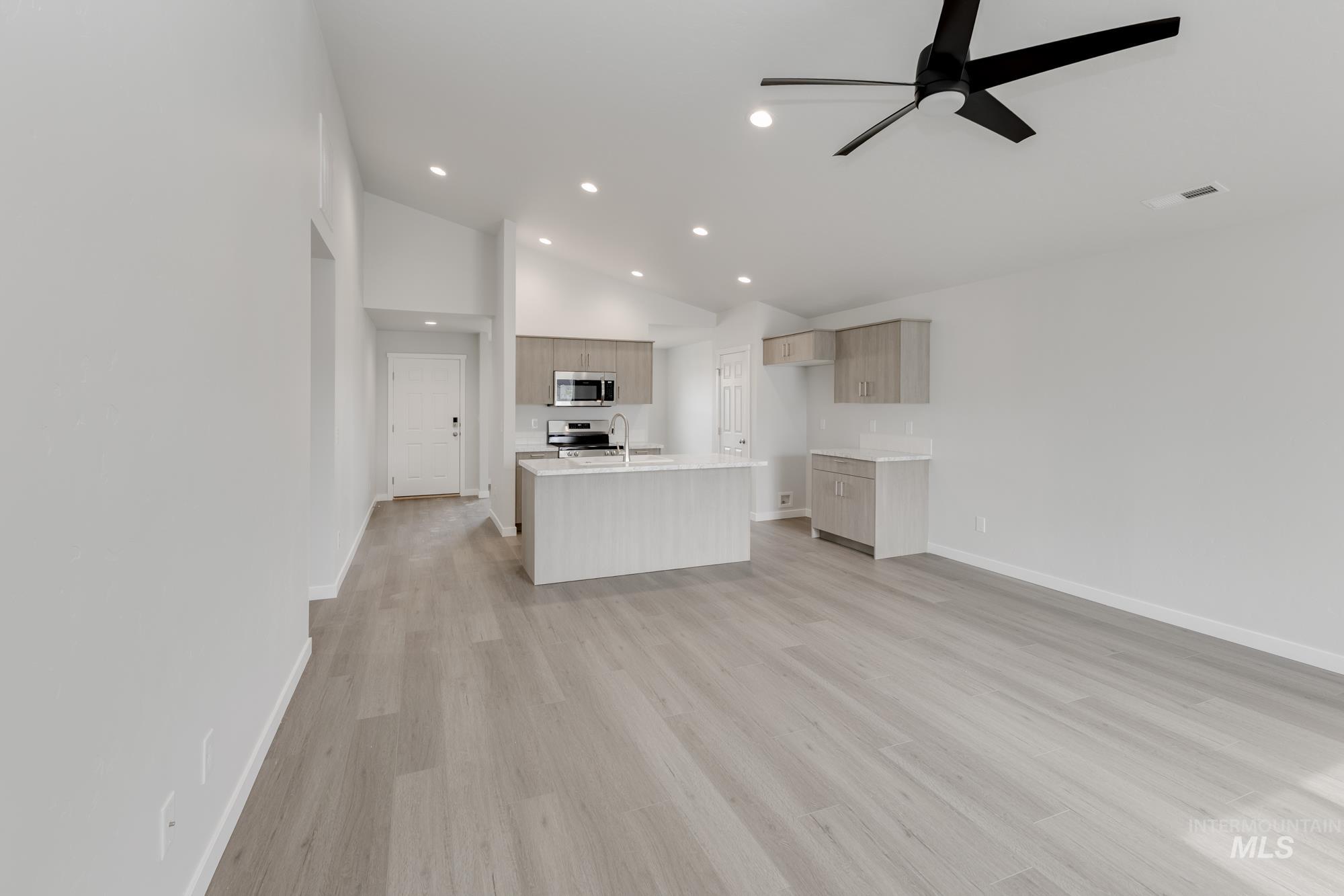 Unfurnished living room with recessed lighting, a ceiling fan, light wood finished floors, and high vaulted ceiling