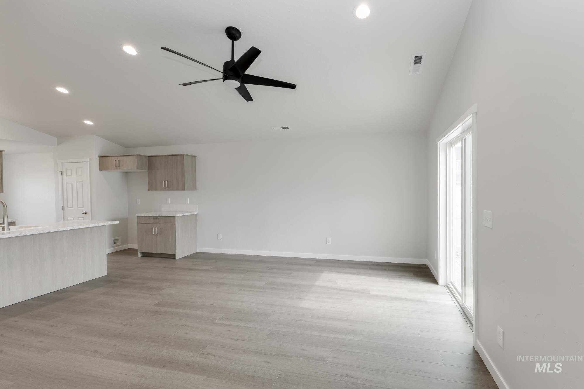 Unfurnished living room with lofted ceiling, ceiling fan, recessed lighting, and light wood finished floors