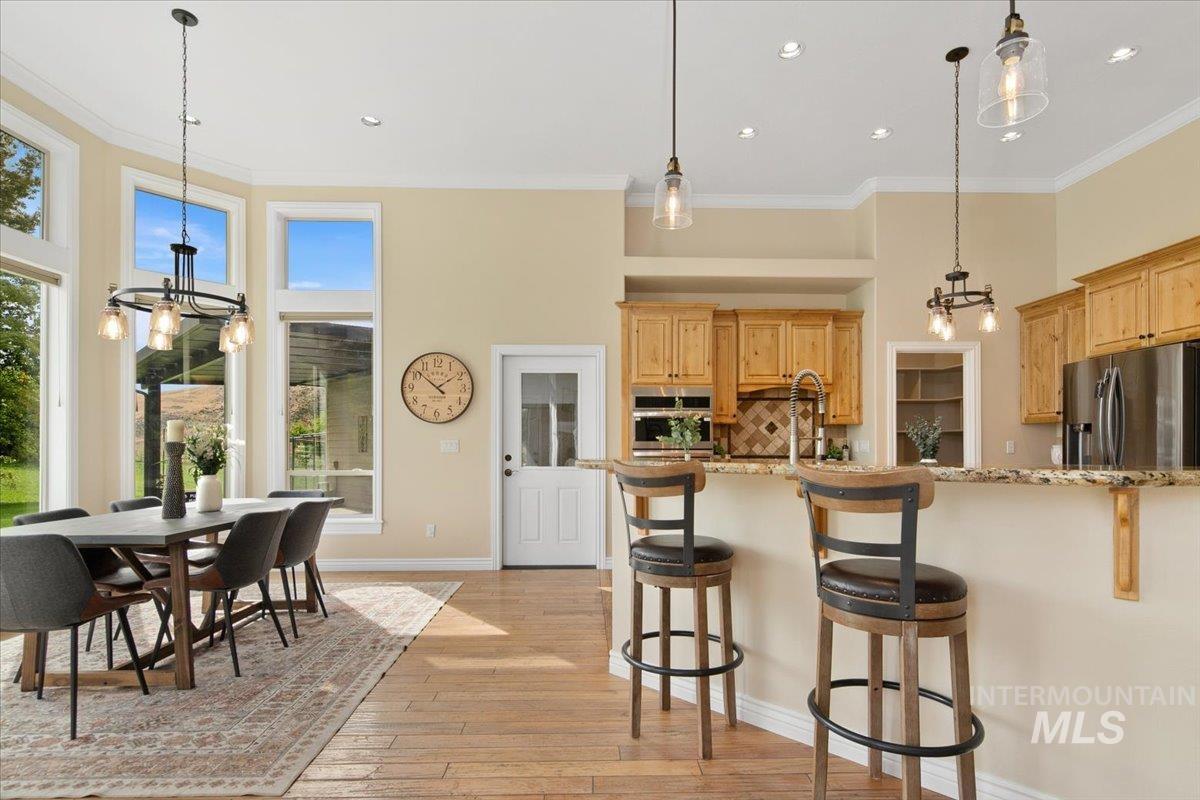 Kitchen with a chandelier, decorative backsplash, crown molding, decorative light fixtures, and light stone counters