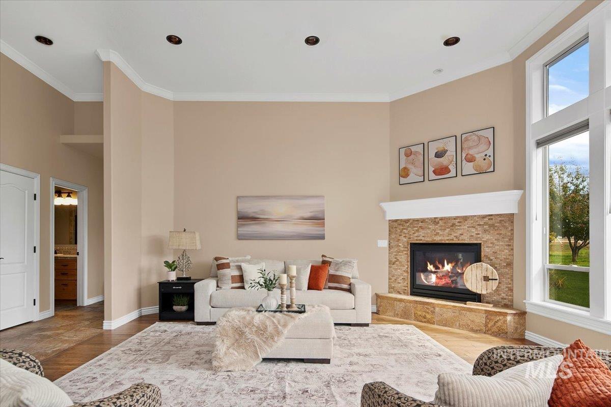 Living room featuring crown molding, a fireplace, wood finished floors, and a high ceiling