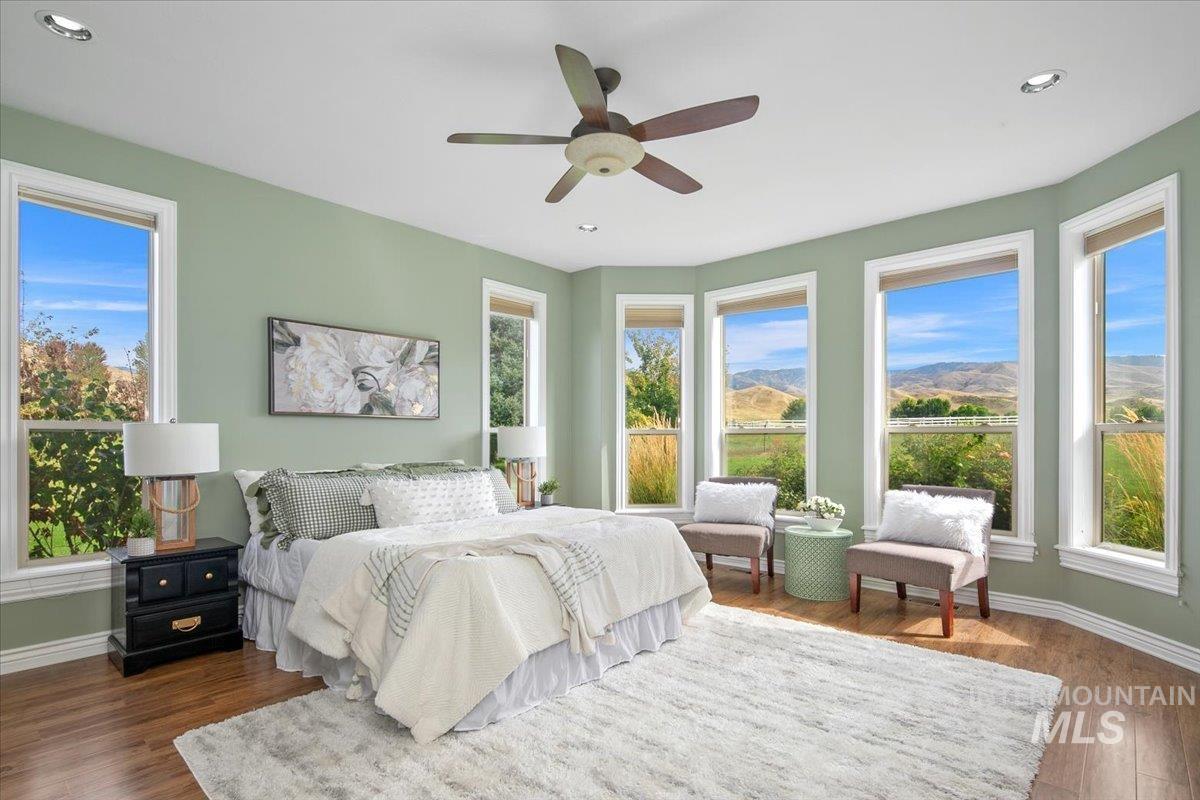 Primary bedroom with dark wood finished floors, ceiling fan, recessed lighting, and a mountain view.