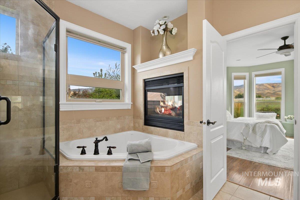 Bathroom with ensuite bathroom, a bath, a stall shower, a multi sided fireplace, and tile patterned floors