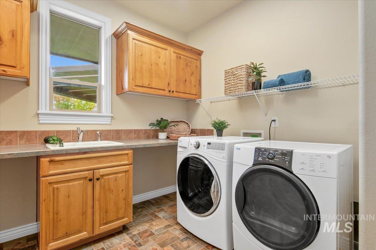 Laundry room with washing machine and clothes dryer, stone finish flooring, and cabinet space